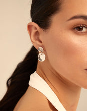 Load image into Gallery viewer, A person viewed from the side wearing a white strapless top and silver hoop earrings with two round shapes.